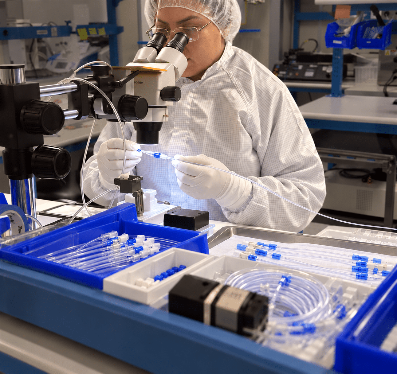 Medical device technician assembling catheter components under a microscope at Pathway MedTech